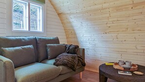 Ein gemütliches Zimmer mit einer Couch, einem Couchtisch und einem Fenster mit Blick auf Bäume.
