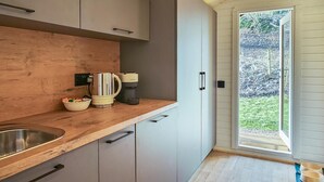 Eine Küche mit Holzarbeitsplatten, einer Spüle, Schränken, einer Kaffeemaschine und Blick ins Freie.