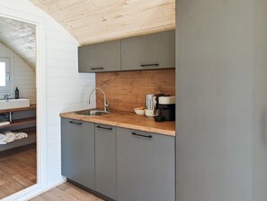 Une cuisine dotée d’un plan de travail en bois, de meubles gris, d’un évier en acier inoxydable et d’une machine à café.
