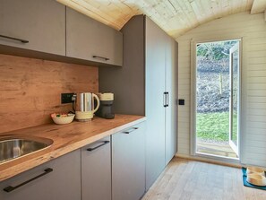 Une cuisine dotée de plans de travail en bois, d’un évier, de placards, d’une machine à café et offrant une vue sur l’extérieur.