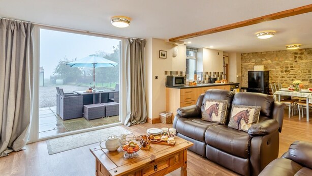 A spacious living room with a leather sofa, a dining area, and a kitchen. - 2 Bed in Thornton Watlass (oc-m30203) (Thornton Watlass)
