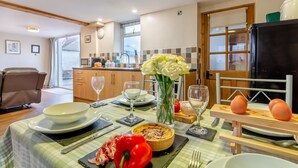 A dining area with a table set for two, featuring plates, glasses, a vase with flowers, a red bell pepper, and a pie. - 2 Bed in Thornton Watlass (oc-m30203) (Thornton Watlass)