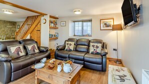 A cozy living room with leather sofas, a wooden coffee table, and a TV mounted on the wall. - 2 Bed in Thornton Watlass (oc-m30203) (Thornton Watlass)