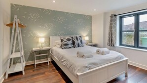 A bedroom with a bed, nightstands, a ladder, and a window with curtains. - 3 Bed in Heacham (oc-t30182) (Heacham)