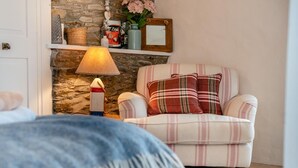 Ein gemütliches Zimmer mit einem Karo-Sessel, einer Lampe und einer Steinwand.