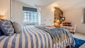 Ein Schlafzimmer mit einem großen Bett, einer Steinwand, einem Kamin und einem Fenster.