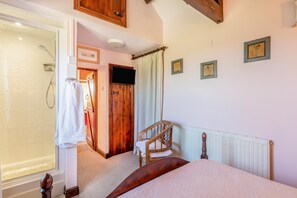 A bedroom with a bed, a wooden chair, a shower, and a door leading to another room. - 1 Bed in Ilfracombe (oc-c30176) (Ilfracombe)