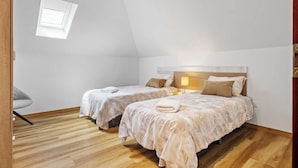 A bedroom with two beds, a small window, and a wooden floor. - Apartment Lurdes (Arco da Calheta)