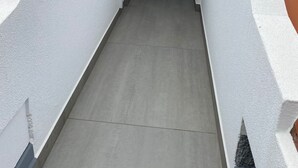 A narrow, enclosed passageway with a tiled roof and white walls, leading to a door. - Apartment Lurdes (Arco da Calheta)