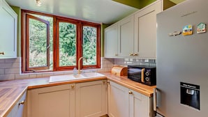 Eine Küche mit Einbau-Mikrowelle, Wasserspender und Spüle mit Fenster darüber.