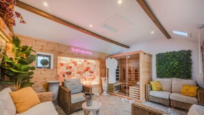 Une salle de spa aux murs en bois, avec une table de massage, un coin salon doté de meubles en osier et un mur végétal.