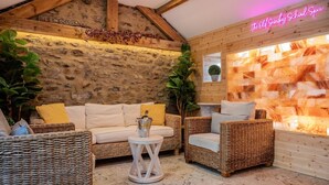 Ein gemütliches Zimmer mit Steinwand, Holzbalken, Korbmöbeln und einer Neonreklame.