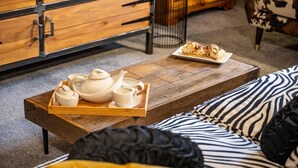 A wooden coffee table with a tray holding a teapot, cups, and saucers, a plate of pastries, and a black metal lamp. - 3 Bed in Richmond (oc-t30197) (Richmond)