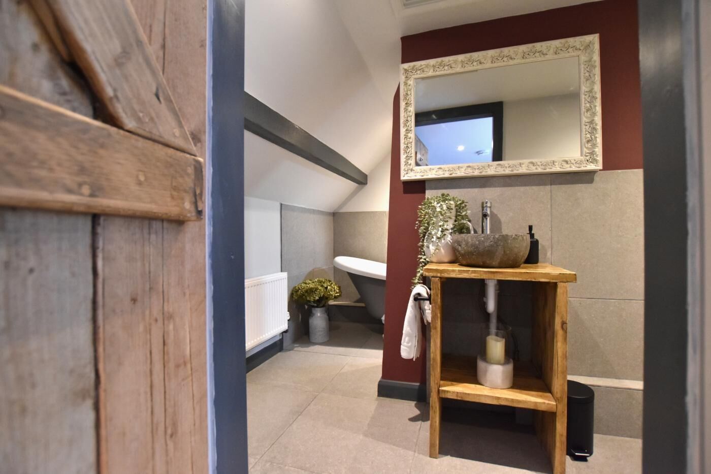 A modern bathroom with a wooden vanity, a large mirror, and a white sink.