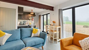A modern living room with a sofa, a dining table, and a view of the outdoors. - 3 Bed in Ashover (oc-w30175) (Ashover)