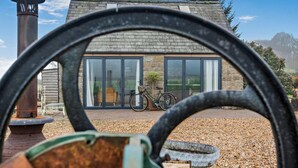 A stone building with large glass doors, a bicycle, and a rustic chimney. - 3 Bed in Ashover (oc-w30175) (Ashover)