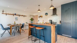 A modern kitchen with a central island, bar stools, pendant lighting, and a blue accent wall.