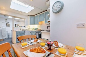 Un desayuno con cruasanes, jugo de naranja y un reloj en la pared.