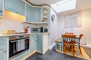 A kitchen with teal cabinets, a microwave, a toaster, and a dining table with chairs. - 2 Bed in Matlock (oc-h30164) (Winster)