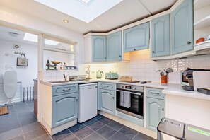 Une cuisine moderne avec des meubles de couleur bleu clair, un lave-vaisselle, un four et une machine à café.