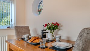 Taula de dinar amb croissants, cafetera, tasses i un ram de flors vermelles.