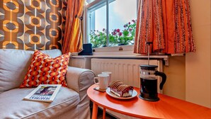 Een gezellige zithoek met een bank, salontafel, radiator en een raam met gordijnen.