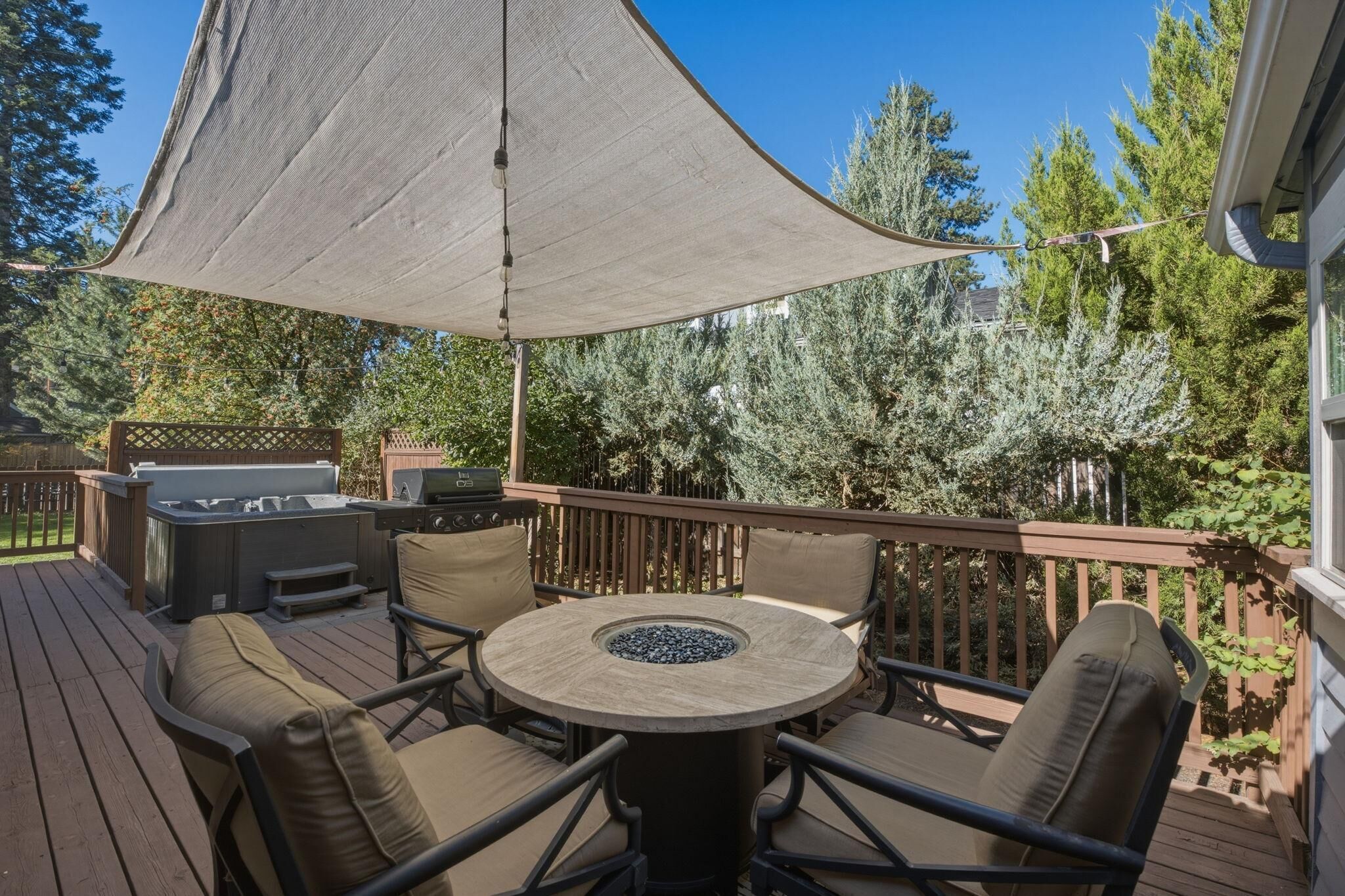 A deck with a round table and chairs, a grill, and a hot tub.