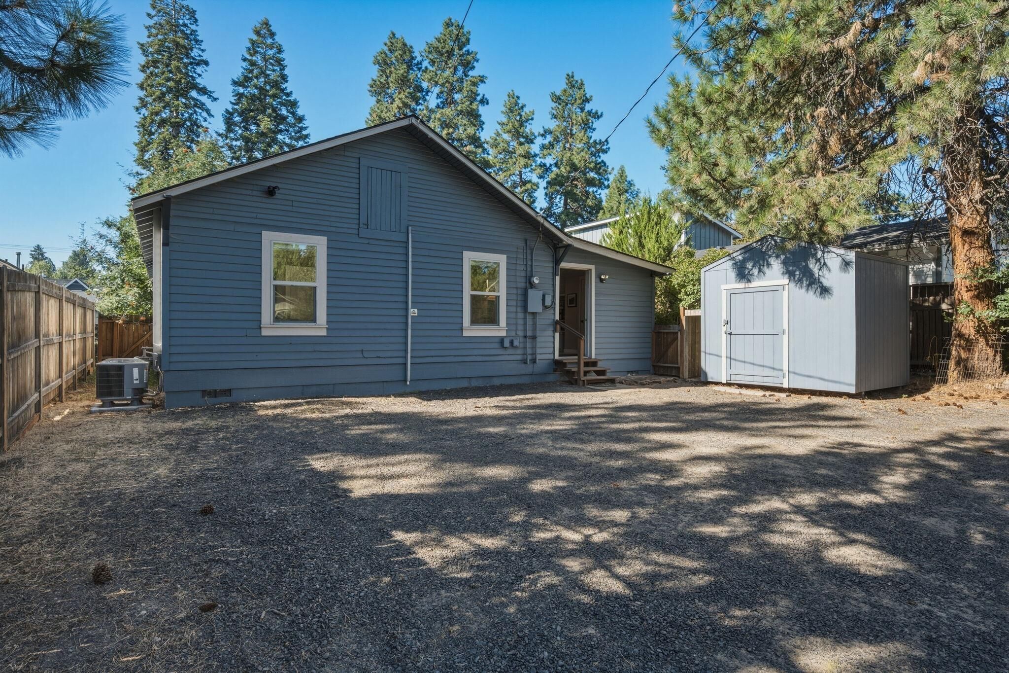 A single-story house with a garage, a small shed, and a fenced yard.