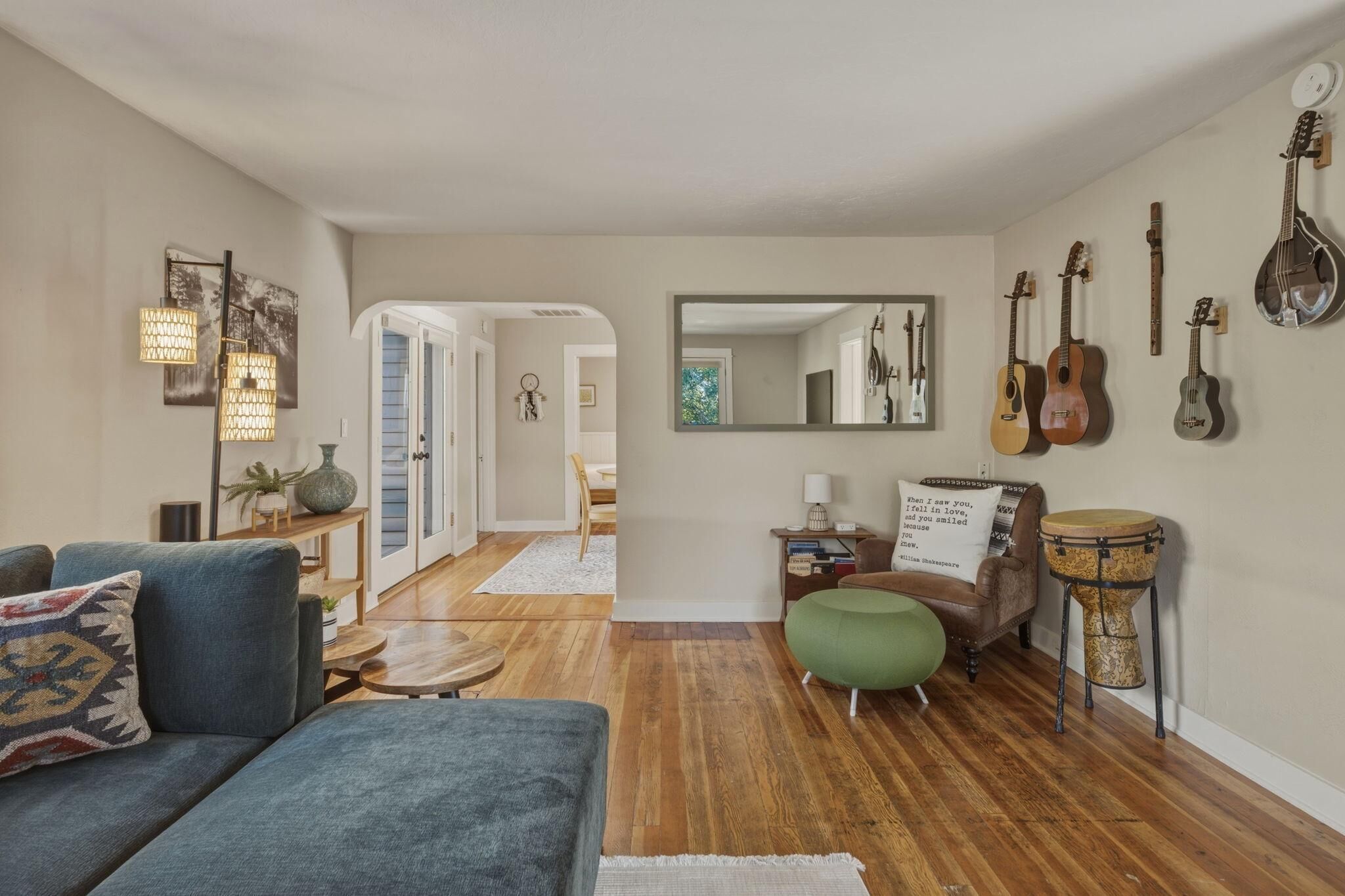 A living room with a sofa, a coffee table, a chair, a drum, and a mirror on the wall.