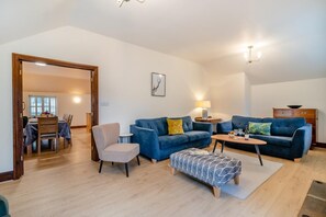 Un salon spacieux comprenant un coin repas, un ensemble de canapés, une table basse et une cheminée.