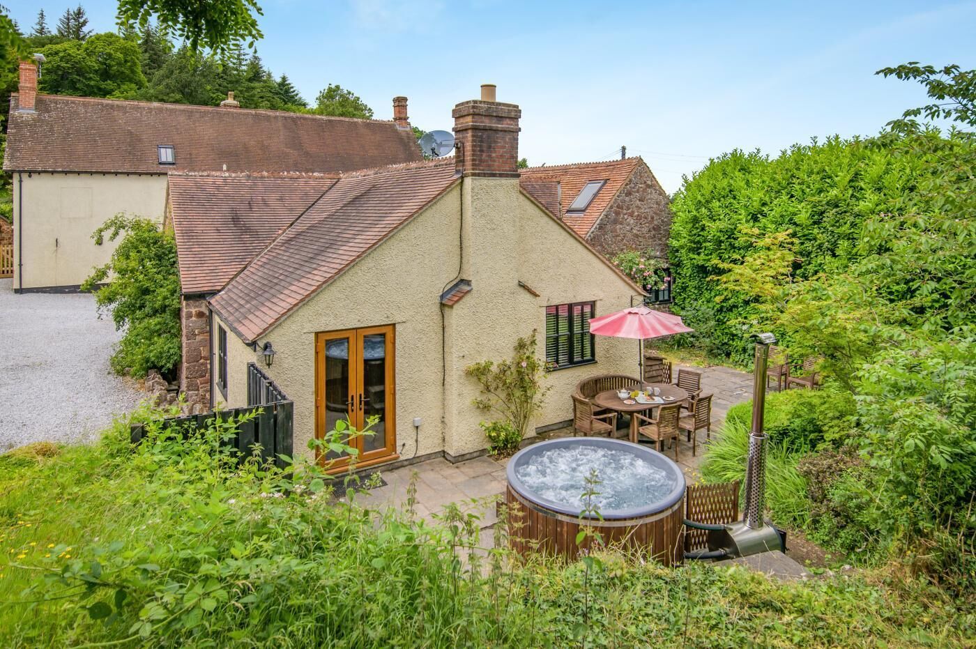 Ein Haus mit Steinaußenwand, einer Holztür, einer Terrasse mit Gartenmöbeln und einem Whirlpool.