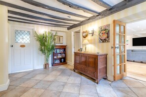 A room with a wooden cabinet, a bookshelf, a potted plant, and a door with a glass panel.