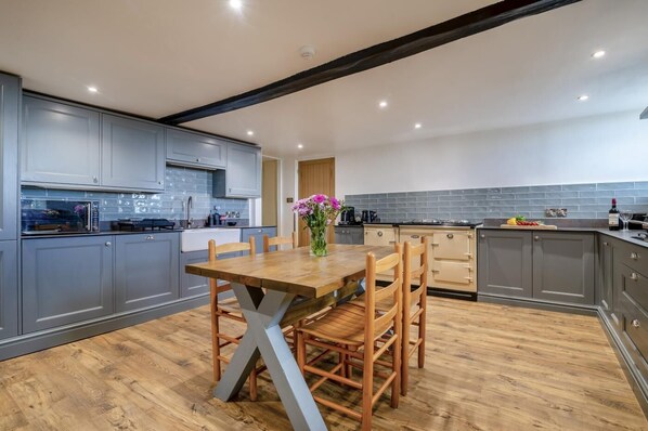 A modern kitchen with grey cabinets, a wooden dining table, and a vase with flowers.