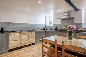 A kitchen with grey cabinets, a wooden dining table, and a vase of flowers.