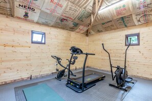 A gym with exercise equipment, wooden walls, and a window.