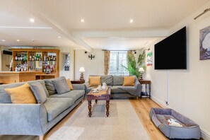 A living room with a sofa, a coffee table, a TV, and a pet bed.