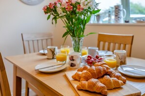 A breakfast table with croissants, fruit, and juice. - 3 Bed in Watchet (oc-c29959) (Watchet)