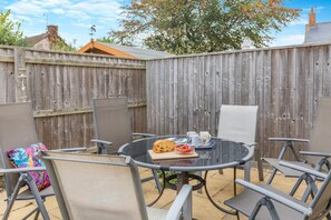 An outdoor patio with a round table, chairs, and a wooden fence. - 3 Bed in Watchet (oc-c29959) (Watchet)