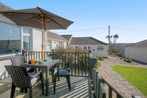 A patio with a table and chairs, a large umbrella, and a view of neighboring houses. - 2 Bed in Mullion (oc-k7968) (Mullion)