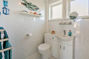 A bathroom with a toilet, sink, and decorative fish wall art. - 2 Bed in Mullion (oc-k7968) (Mullion)