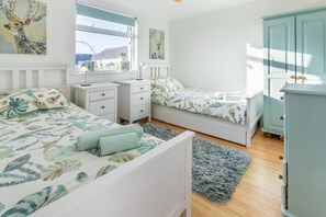 Una camera da letto con due letti, un comodino, una cassettiera e una finestra vista.