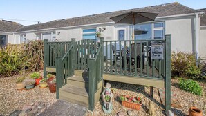 A house with a wooden deck, a covered patio, and a garden with potted plants. - 2 Bed in Mullion (oc-k7968) (Mullion)