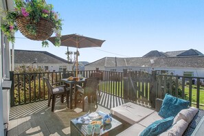 A patio with a table, chairs, a hanging plant basket, and a wooden fence. - 2 Bed in Mullion (oc-k7968) (Mullion)