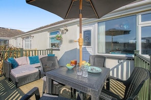 An outdoor patio with a table, chairs, and a hanging light fixture.
