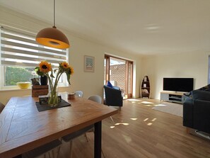 A modern living room with a wooden dining table, a sofa, a TV, and a bookshelf. - 2 Bed in Norton (oc-l30264) (Freshwater)