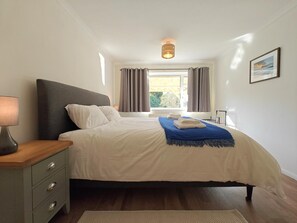 A neatly made bed with white linens, a blue throw blanket, and a bedside lamp. - 2 Bed in Norton (oc-l30264) (Freshwater)