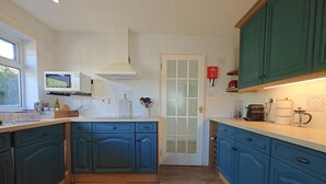 Una cocina con armarios color turquesa, un microondas y una cafetera.