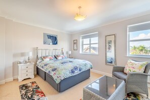 A bedroom with a bed, bedside tables, a chair, a glass coffee table, and artwork on the walls. - 3 Bed in Littlestone (oc-s30210) (Littlestone)