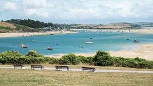 Ein Küstenblick mit Sandstrand, Booten und Bänken am Ufer.