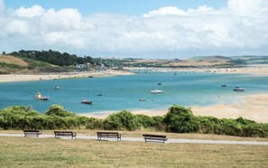 A coastal view with a sandy beach, boats, and benches along the shore. - 4 Bed in Winnards Perch (oc-k30259) (Winnard's Perch)